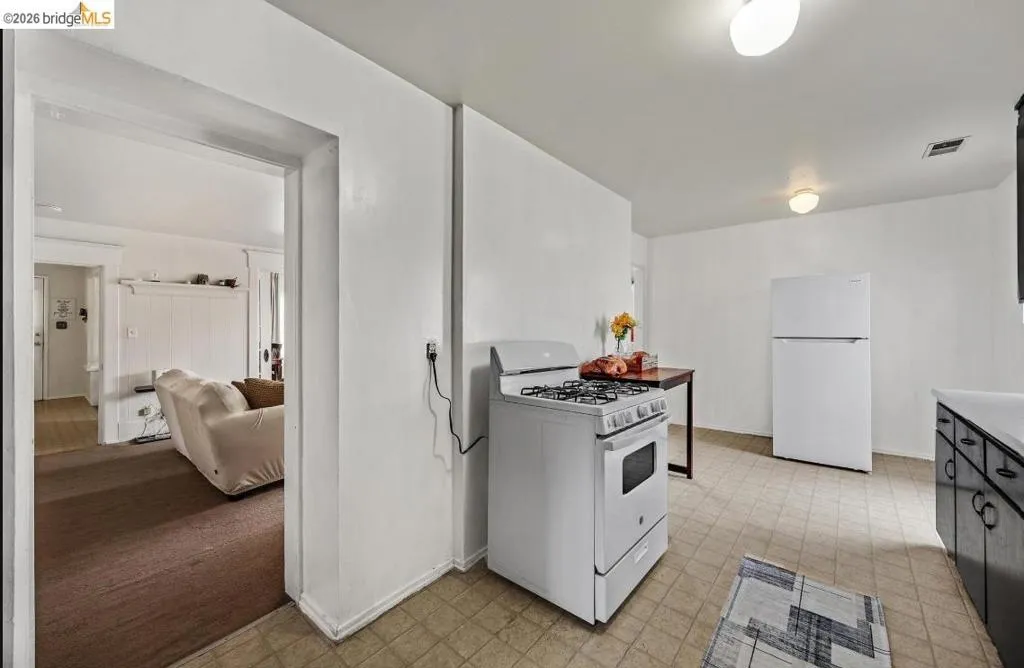 Kitchen featuring a white gas range, white refrigerator, and black cabinetry with white countertops