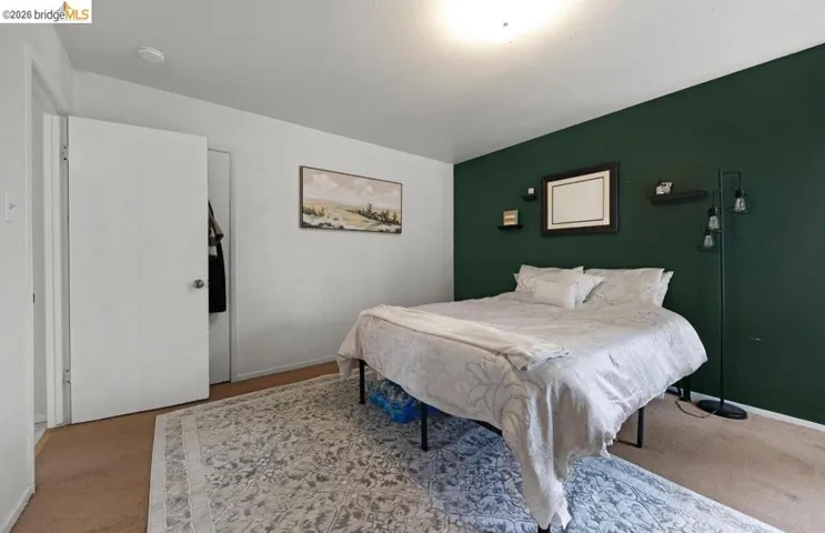 Bedroom featuring a dark green accent wall, white painted walls, and carpet flooring