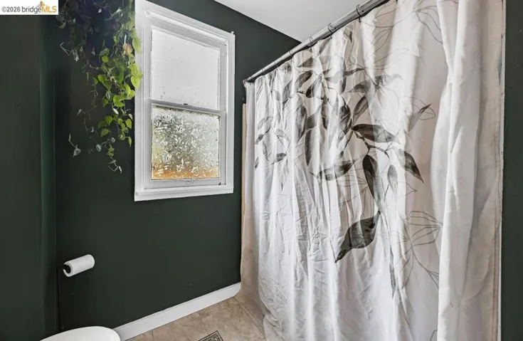 Bathroom featuring dark green walls, a window with frosted glass, and tile flooring