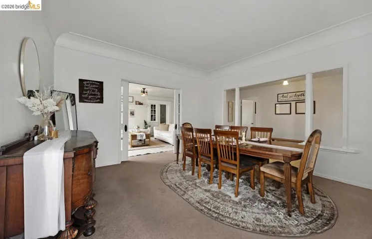 Spacious dining area featuring neutral carpeting, white walls, and elegant crown molding