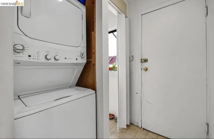 Stackable white washer and dryer unit, integrated within a functional laundry closet
