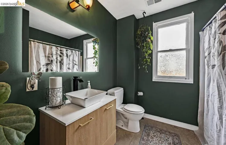 Bathroom featuring a wood-finish vanity with a white countertop and a vessel sink