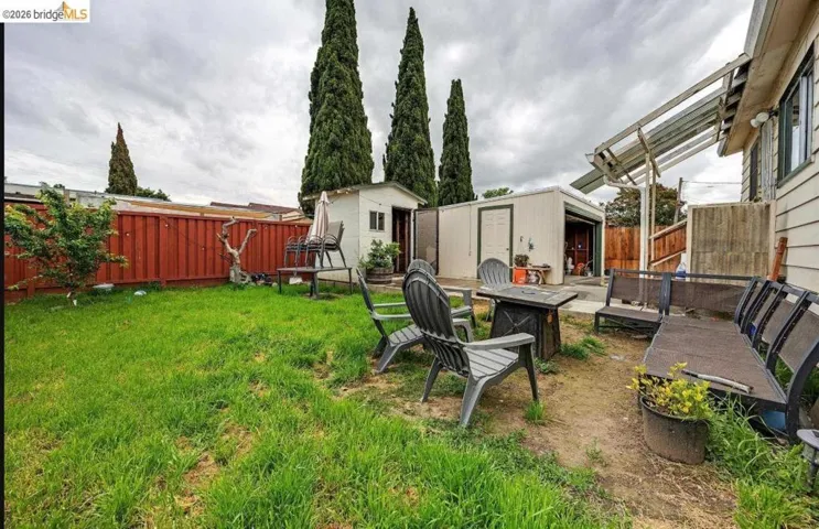 Expansive backyard featuring a lush lawn, privacy fencing, and mature vertical landscaping