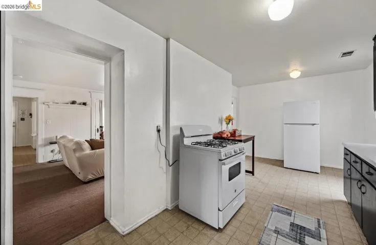 Kitchen featuring a white gas range, white refrigerator, and black cabinetry with white countertops