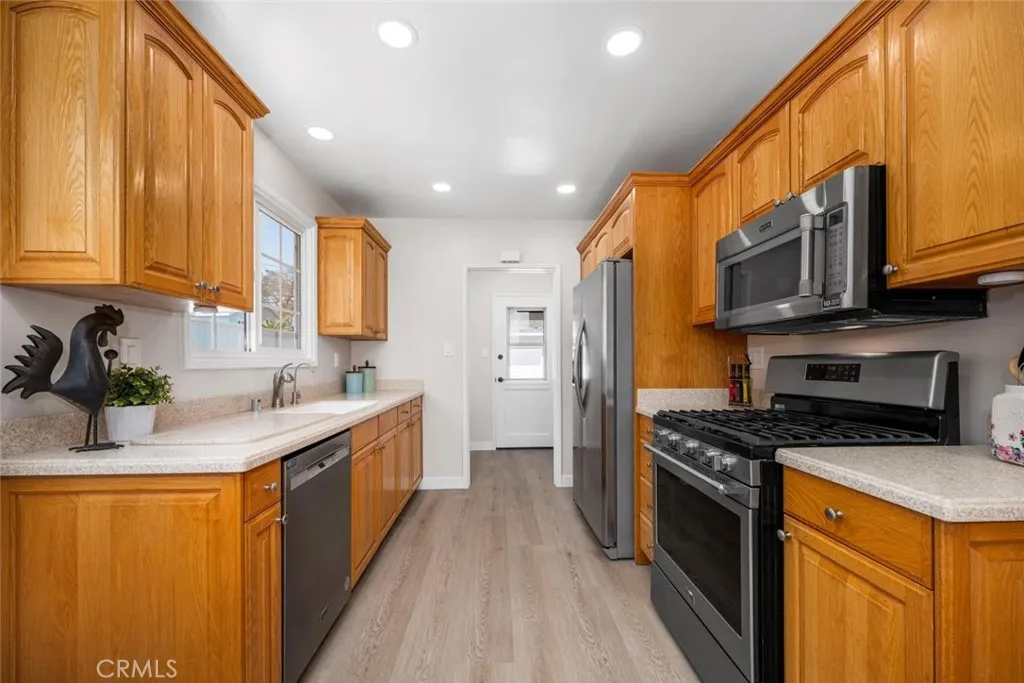 The kitchen showcases handsome oak cabinetry complemented by sleek Corian countertops for a classic yet practical design.