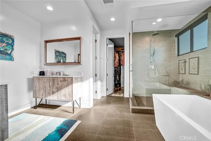 Primary bathroom with custom cabinetry and tile, soaking tub, and extra spacious shower, walk-in closet