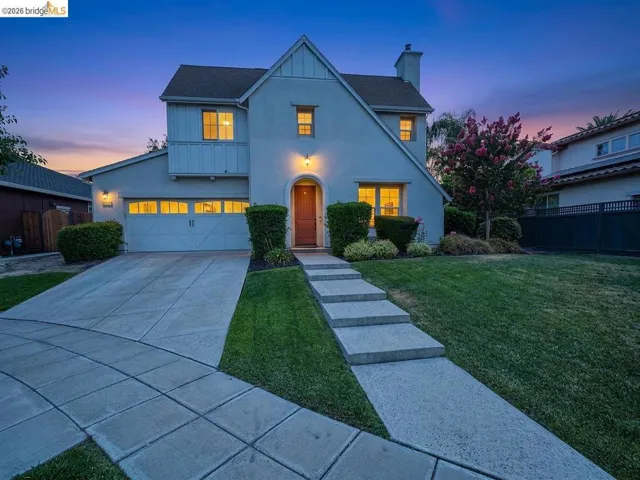 Stucco exterior with a peaked roofline, arched entry, and a two-car garage