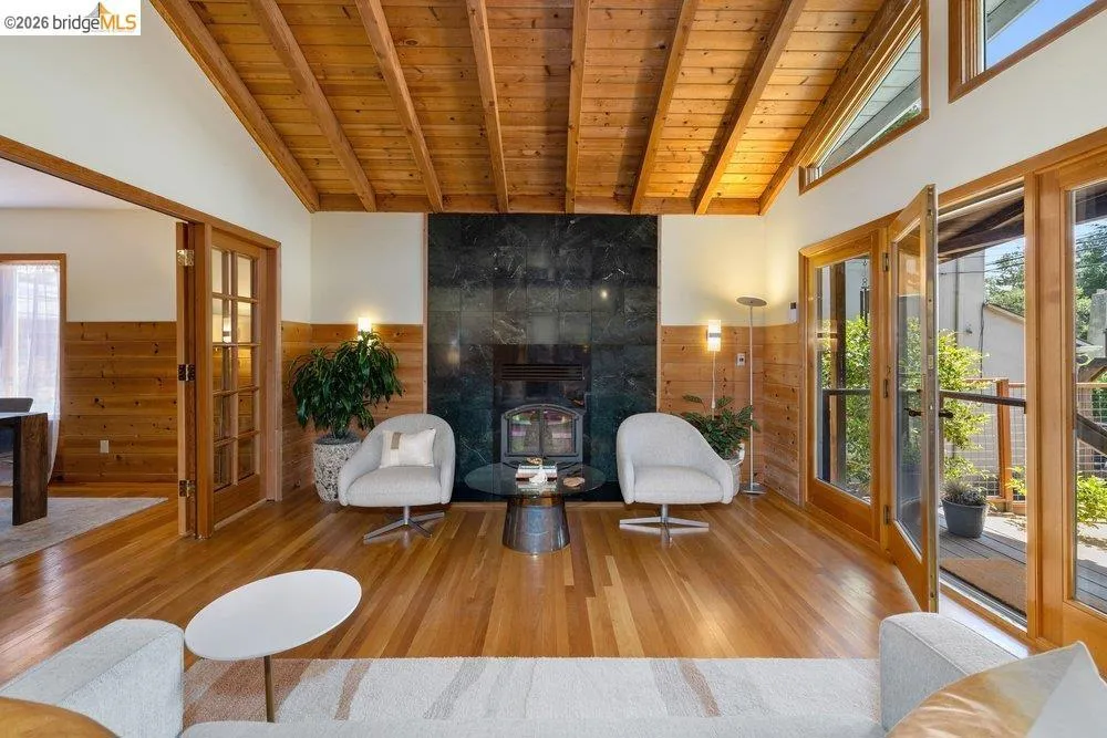 Vaulted wood plank ceiling over a living area with a dark stone fireplace surround