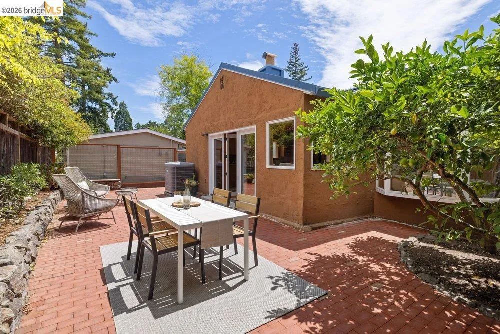 Brick paver patio featuring an earth-toned stucco exterior, white-framed windows, and sliding glass patio doors