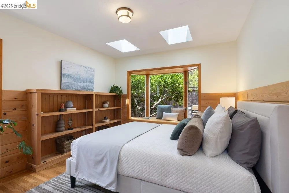 Wood-paneled room featuring a built-in window bench, two skylights, a built-in wooden bookcase, and wood-finish flooring