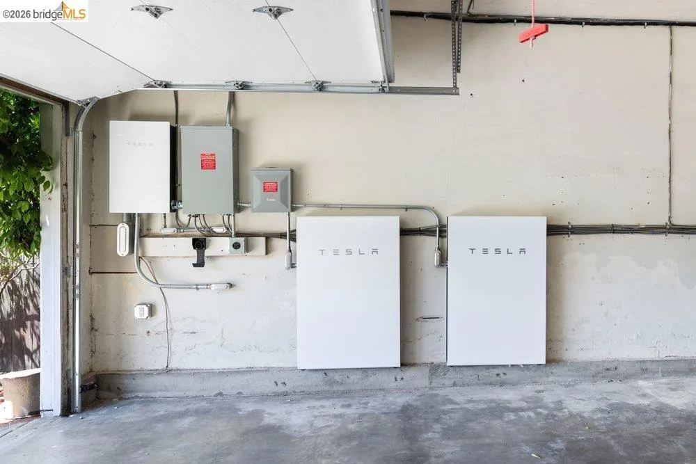 Integrated energy storage system with two Tesla Powerwall units and associated electrical components mounted on a neutral-toned wall