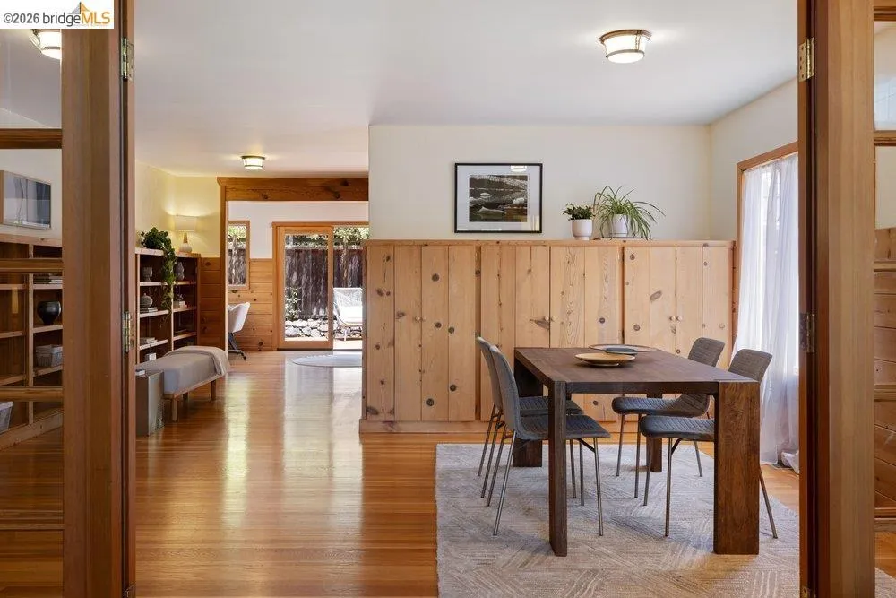 Dining area featuring wood paneling and a large window with sheer drapes