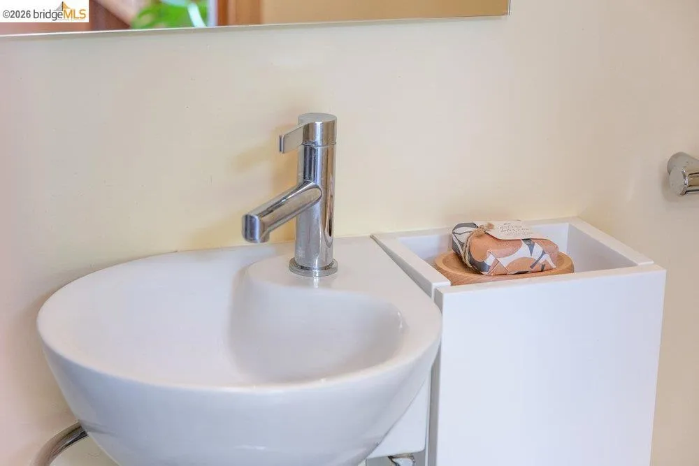 Modern white ceramic vessel sink with a polished chrome faucet, set against a light-toned wall