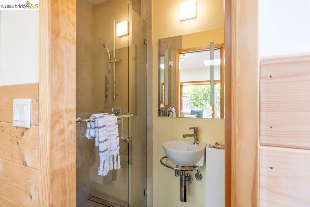 Modern bathroom featuring a glass-enclosed shower with tile surround, a vessel sink with chrome fixtures, and a framed mirror