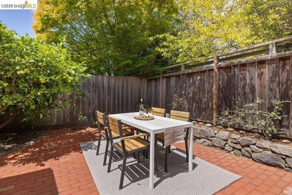 Private outdoor patio featuring brick pavers, a wood privacy fence, and a stone retaining wall