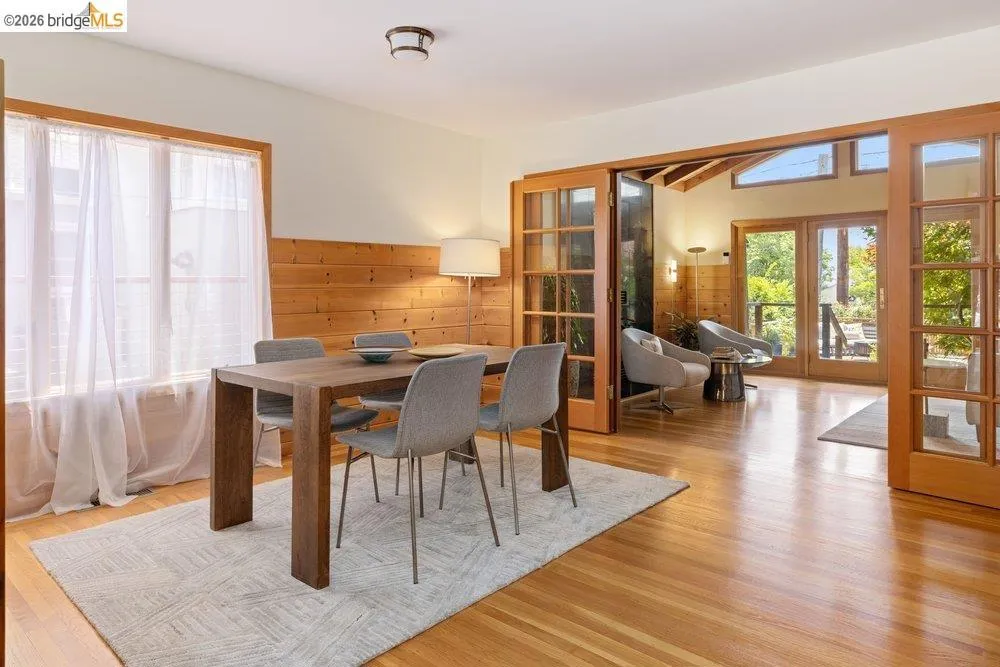 Dining area with wood-finish flooring, half-wall wood paneling, and an overhead light fixture