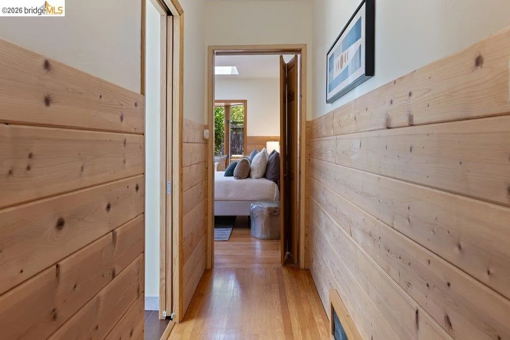 Hallway featuring wood-finish paneling, hardwood flooring, and a recessed air vent