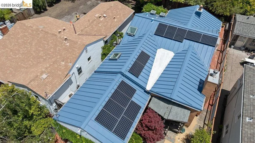 Blue metal standing seam roof with multiple skylights and integrated solar panels