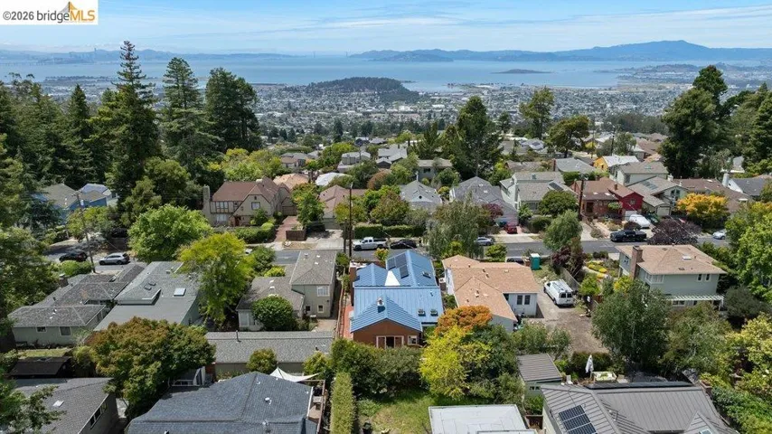 Neighborhood setting featuring a variety of architectural styles, mature trees, and distant water and mountain scenery