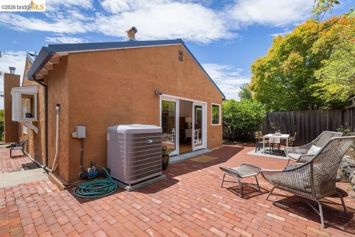 Expansive brick paver patio featuring a stucco exterior, sliding glass door access, and a wood privacy fence