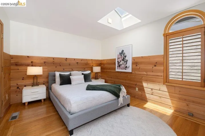 Room featuring wood-finish flooring, a skylight, and wood plank wall paneling