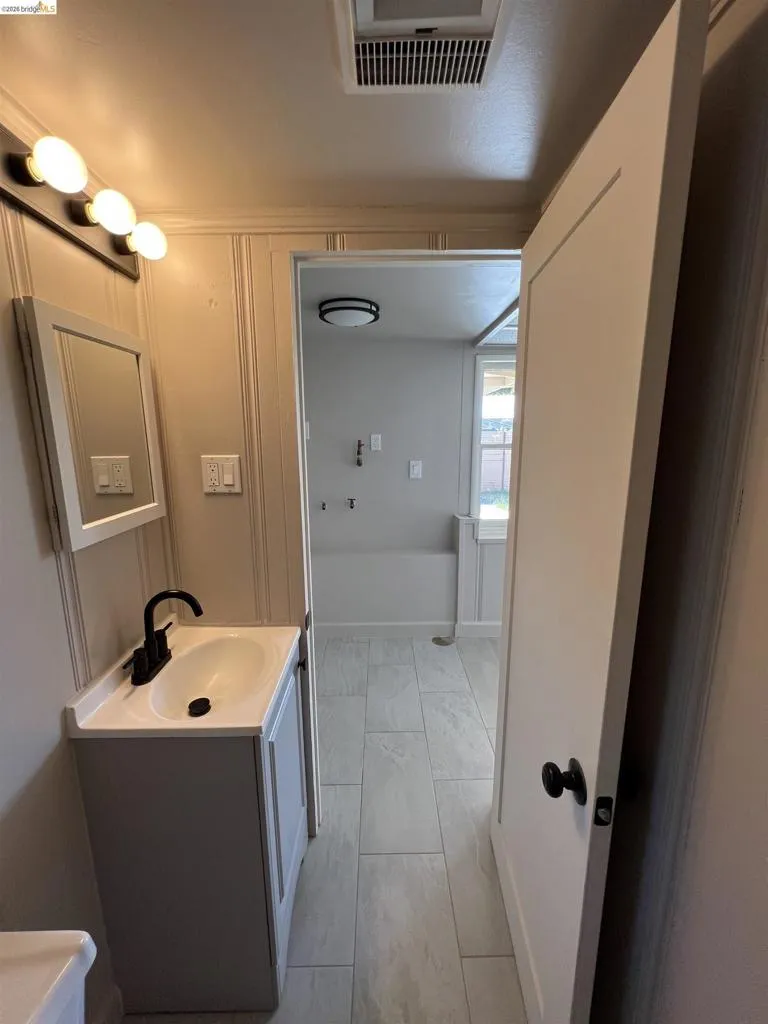 Bathroom vanity featuring a rectangular integrated sink, matte black faucet, and a wall-mounted mirror