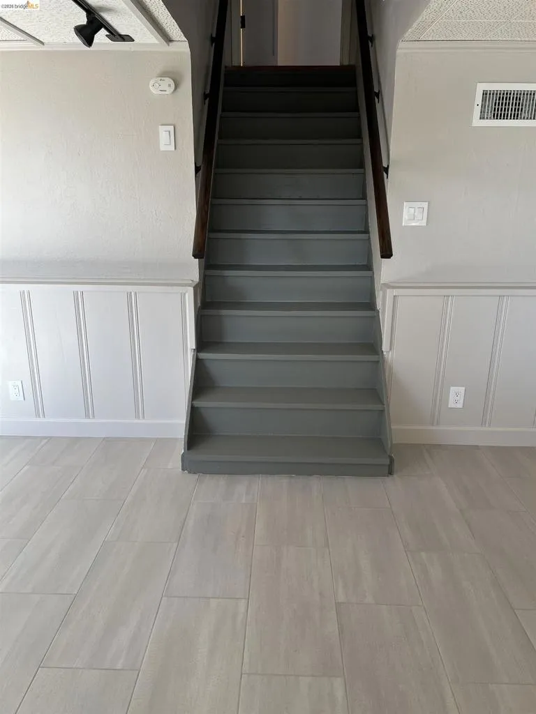 Staircase featuring dark wood handrails and gray treads