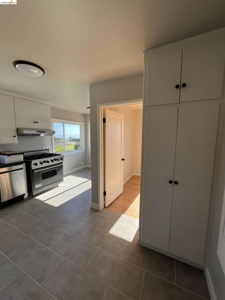 Kitchen featuring stainless steel appliances, a gas range, and white upper and lower cabinetry