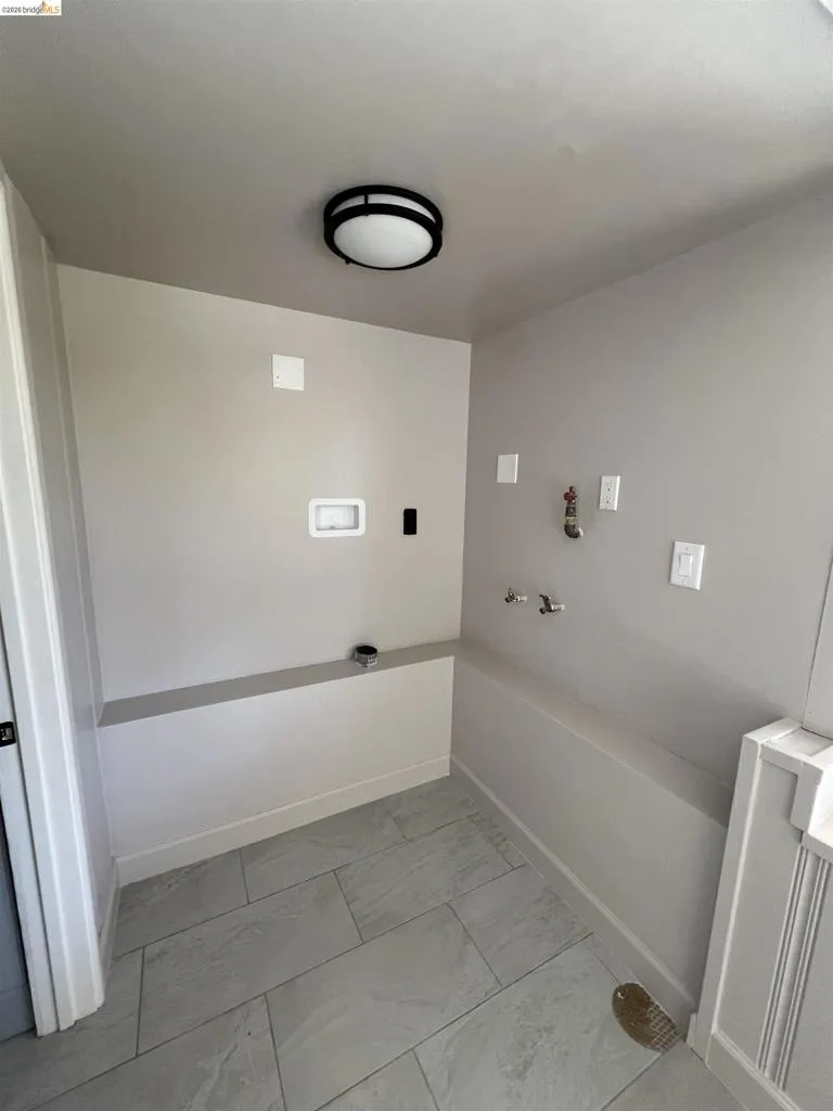 Dedicated utility area featuring tile flooring, neutral wall tones, and overhead flush-mount lighting