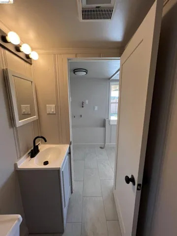 Bathroom vanity featuring a rectangular integrated sink, matte black faucet, and a wall-mounted mirror