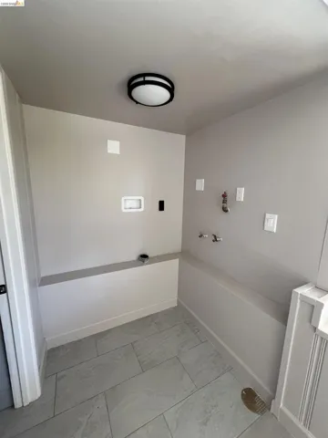 Dedicated utility area featuring tile flooring, neutral wall tones, and overhead flush-mount lighting