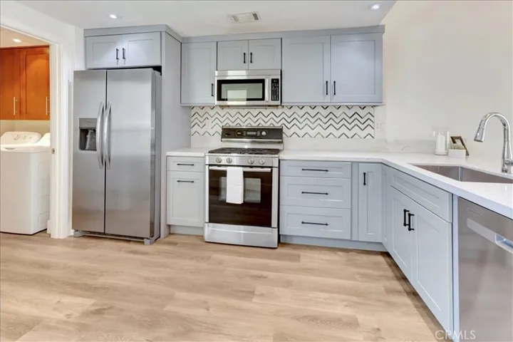 Remodeled kitchen features craftsman style cabinets with black hardware, stainless steel appliances, updated lighting and quartz countertops.