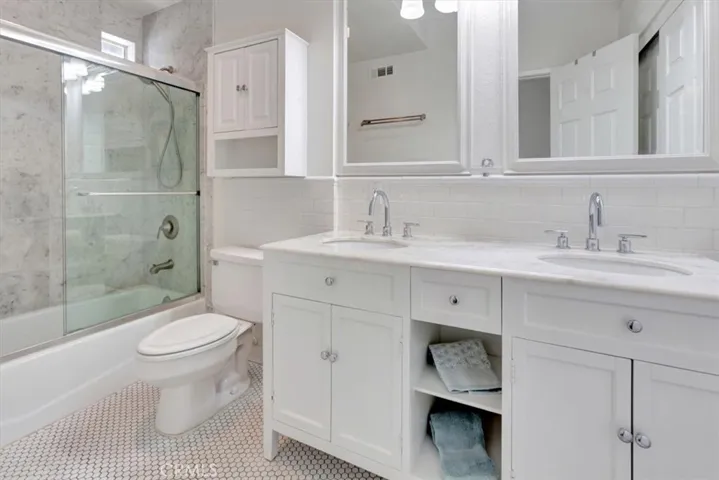 Primary bath remodeled with bright white vanity, tile shower, subway tile walls, stainless steel fixtures and updated lighting