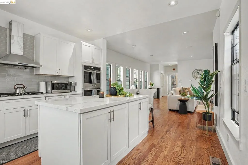 White kitchen with a large island featuring a marble-look countertop and white shaker cabinetry
