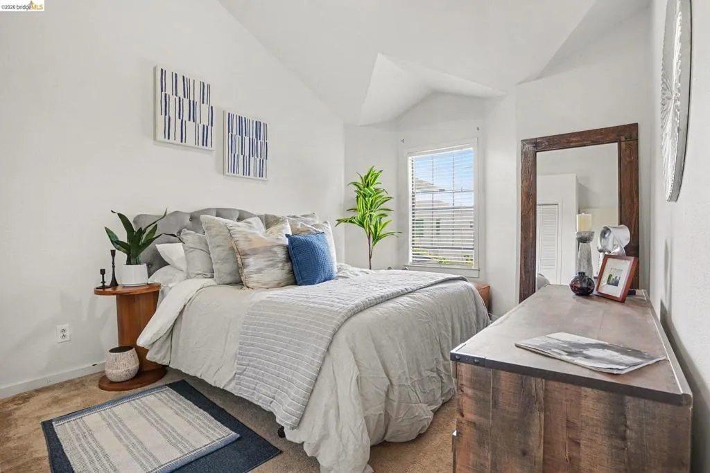 Bright bedroom featuring a vaulted ceiling and window with blinds