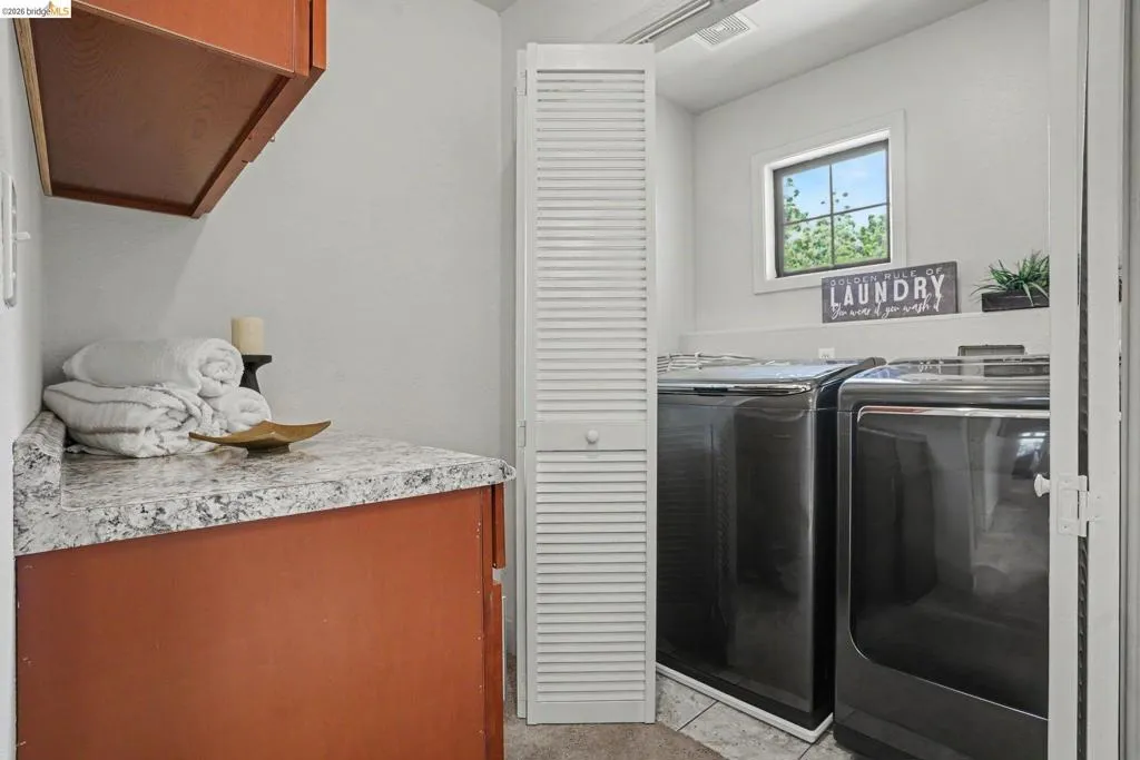 Laundry area featuring a window, built-in shelving, wood-finish cabinetry, and a speckled countertop