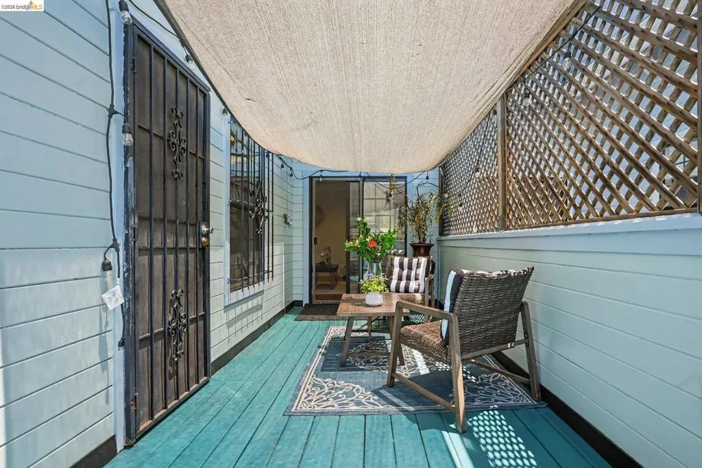 Covered patio area featuring a teal wood-finish deck, a sliding glass door entry, and a decorative security screen door