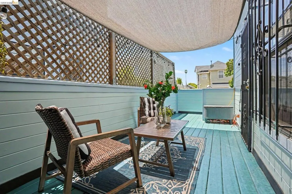 Outdoor deck featuring light blue plank flooring, a lattice privacy screen, and a fabric overhead shade