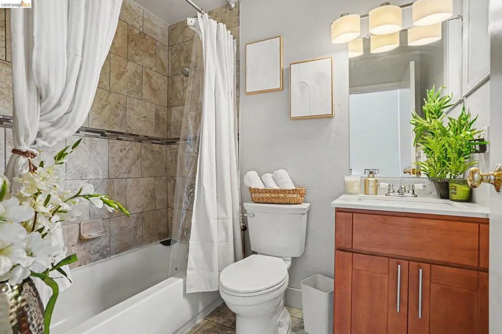 Bathroom featuring a wood-finish vanity with a white countertop, an integrated sink, and a multi-bulb light fixture above the mirror