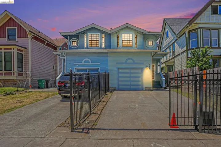 Light blue stucco exterior featuring a two-car garage with horizontal paneling, two prominent bay windows, and a concrete driveway