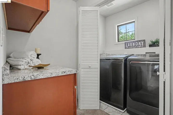 Laundry area featuring a window, built-in shelving, wood-finish cabinetry, and a speckled countertop