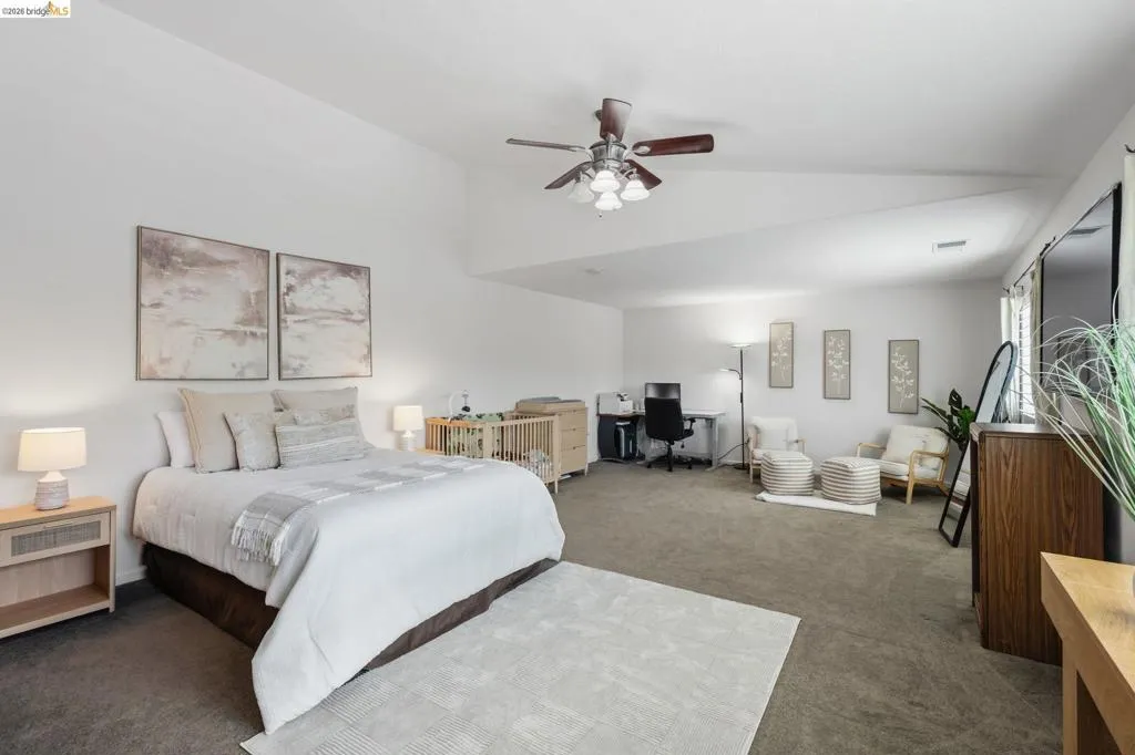 Spacious room featuring carpeting, high vaulted ceilings, a ceiling fan with integrated lighting, and multiple windows providing natural light