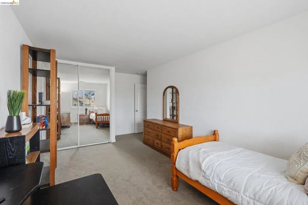 Carpeted room featuring a mirrored sliding door closet, a built-in wooden shelving unit, and a white painted wall