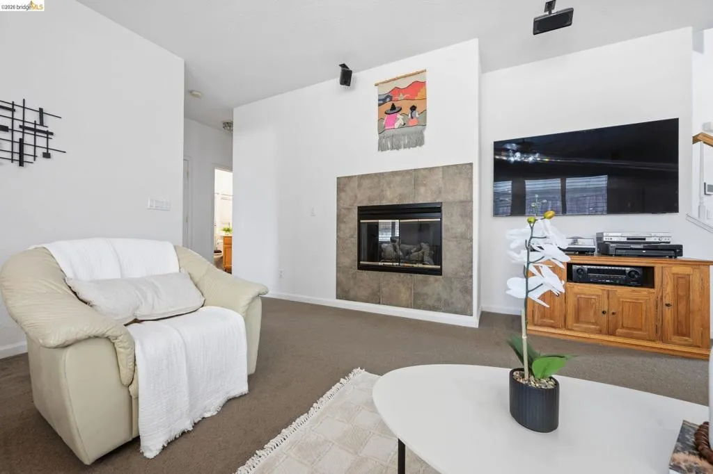 Living area featuring a tiled fireplace with a black insert, high ceilings, and neutral-toned carpeting