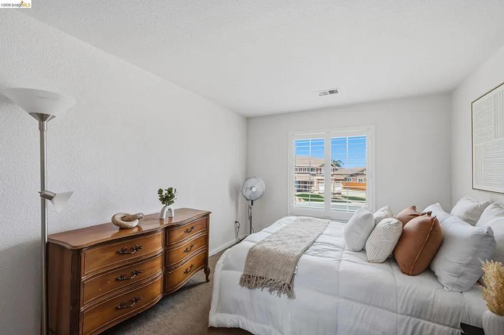 Bedroom featuring a window with white trim, light-colored walls, and a textured ceiling