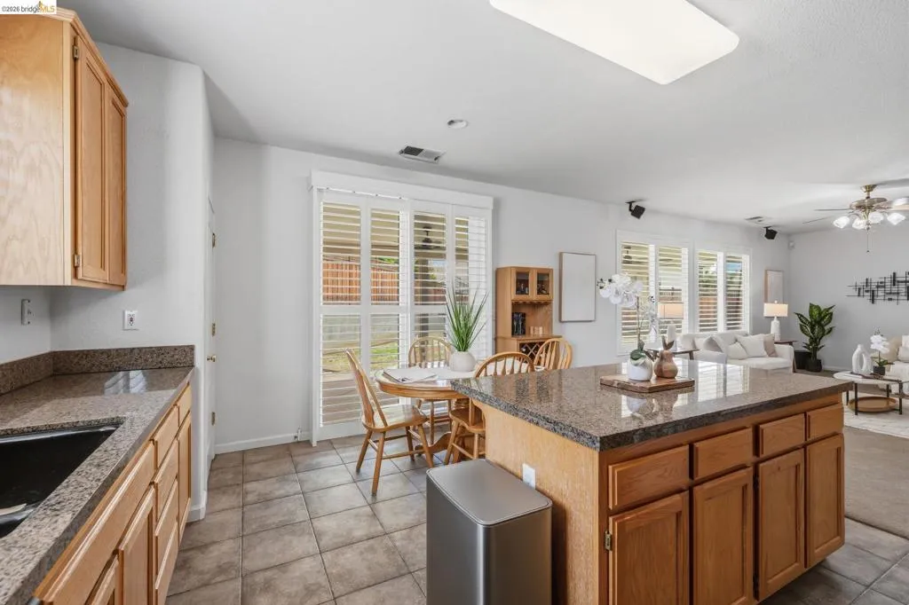 Kitchen featuring granite countertops, wood cabinetry, stainless steel sink, and ceramic tile flooring