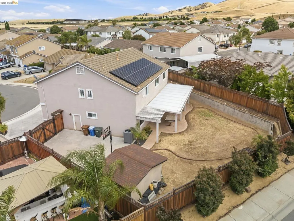 Rear exterior featuring a covered patio, solar panels, and wood fencing