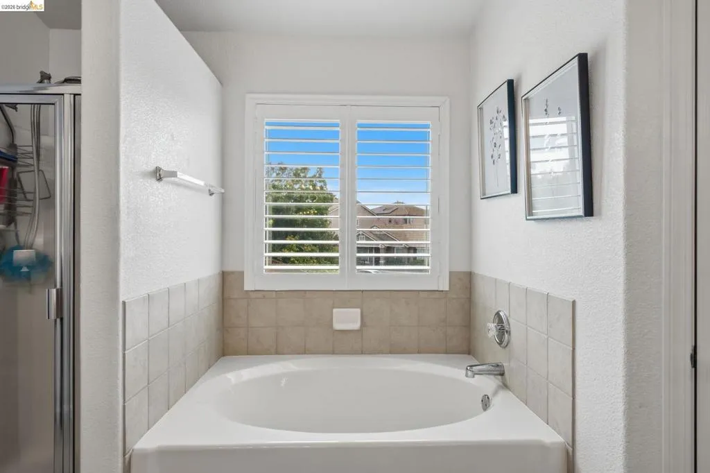Built-in soaking tub with chrome fixtures, surrounded by light-toned tile wainscoting