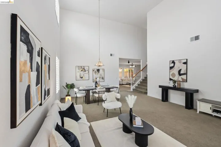 Vaulted ceilings define this open-concept living space, featuring neutral carpeting and white wall finishes
