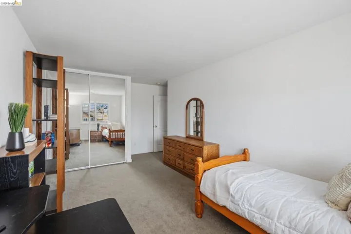 Carpeted room featuring a mirrored sliding door closet, a built-in wooden shelving unit, and a white painted wall